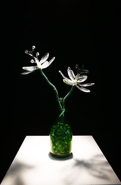 A glass scupture of 2 white flowers in a green vase.