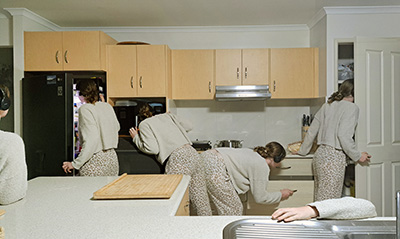 A photograph of the artist doing different things in the kitchen.