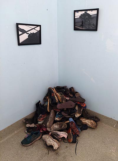 The installation consists of a stack of shoes set in a corner.