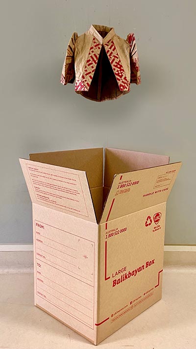 A Bolero hanging above a cardboard box that is labelled 'LARGE Balikbayan Box'