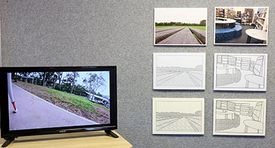 Installation with a monitor showing an outdoor environment on a table to the left, and 6 images on the right wall in 2 columns. The top left image depicts an outdoor scene, and the top right shows a library. Each image has 2 illustrated versions below it