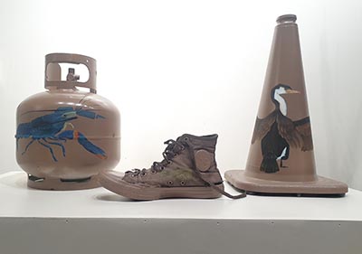 Sculpture featuring a painted small gas bottle, shoe and traffic cone