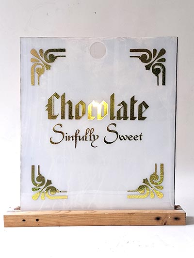 An acrylic sign holder displaying the text: 'Chocolate Sinfully Sweet'