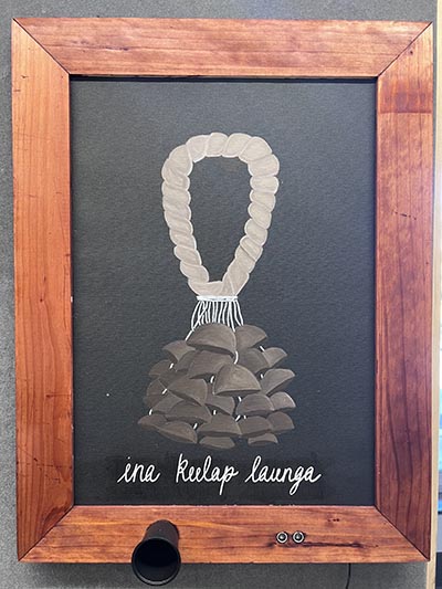 installation featuring an image with the text 'ina kulap launga' in a wooden frame, with a sensor embedded in the frame.