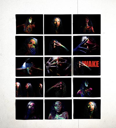 Grid of 3 columns and 5 rows of images, each with a black background showing different human expressions. The image in row 3, column 3 is displayed on an iPad and features the word 'WAKE' in red.