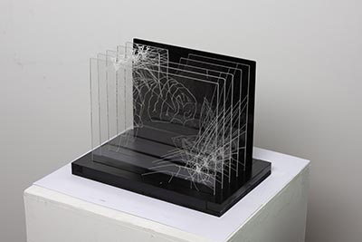 A sculpture of five clear acrylic pieces with organic white line patterns, stacked against a black backing and mounted on a black base.