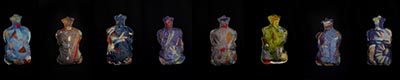 A sculpture featuring a series of eight hot water bottles, each adorned with unique artwork, displayed against a black background.