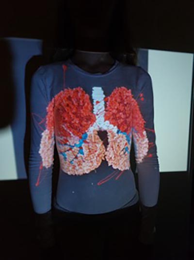 A headless mannequin dressed in a navy blue long shirt featuring an image of lungs on the front.
