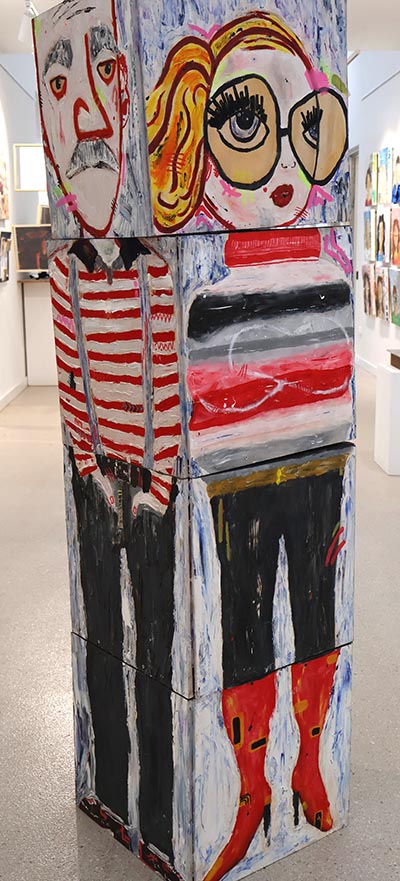 An installation of four stacked blocks, with each side forming a complete painting of a different character spanning the four blocks.