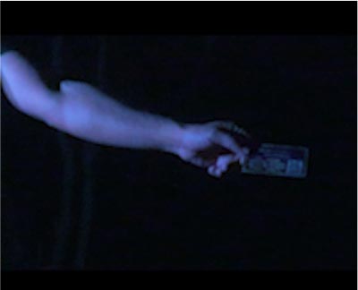 An image of an arm holding a piece of printed material in a dimly lit environment.