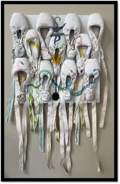 A painting featuring 11 white ballet shoes arranged with 4 shoes stacked on another 4, and 3 placed in the gaps between them. The ribbons hang loosely, and drawings adorn the tops of the shoes.