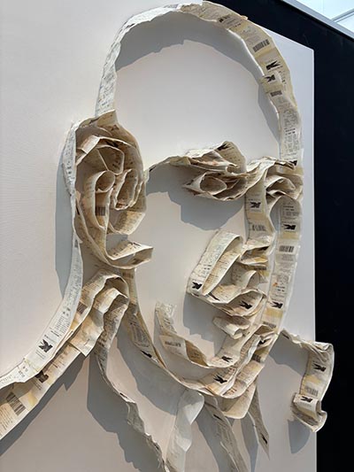 A wall-mounted sculpture of a portrait crafted entirely from Kmart receipts.